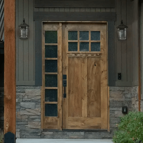 Wooden front door with glass panels on a stone and wooden exterior wall.