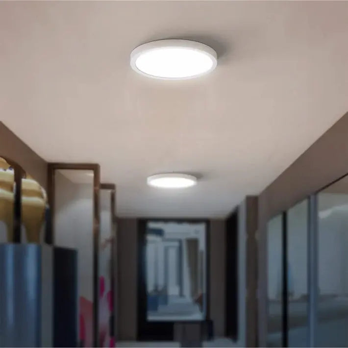 Two round ceiling lights on a beige ceiling with a blurred hallway in the background.
